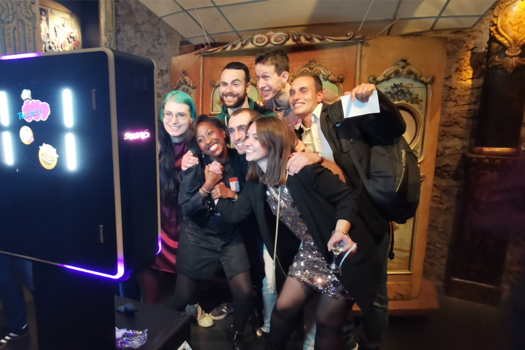3 femmes et quatres hommes se prennent en photo grâce à une borne selfie photobooth lors d'une soirée.