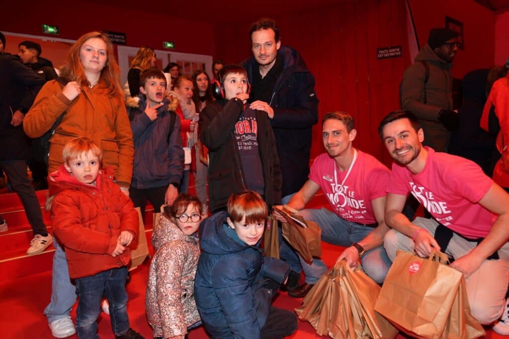Enfants et bénévoles de Tout le monde contre le cancer avec leurs cadeaux au gala de Noël 2023