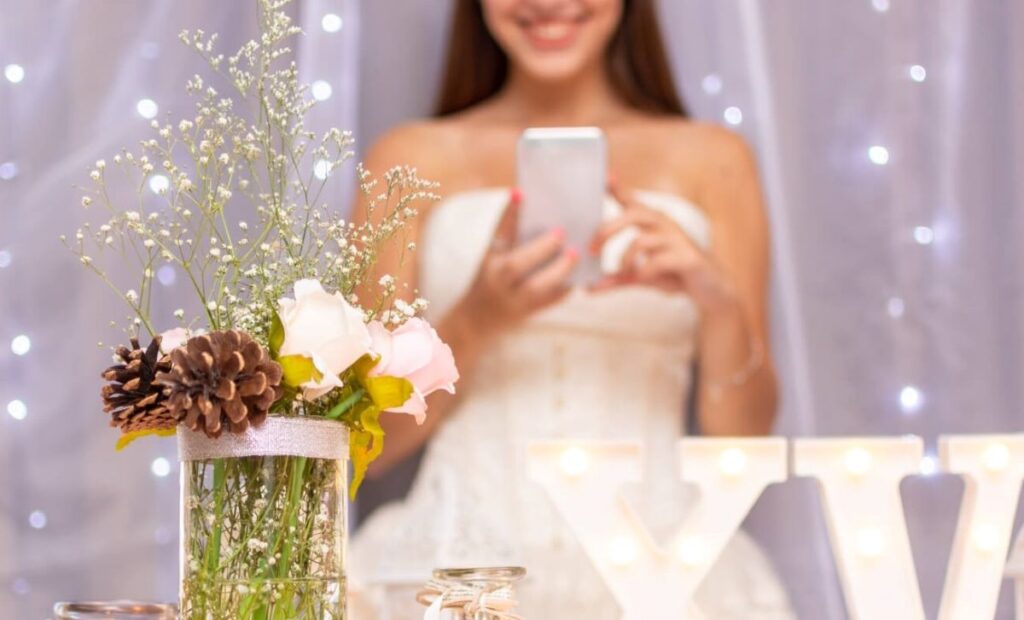 femme mariée robe blanche avec smartphone téléphone dans la main bouquet de fleur blanche dans un vase