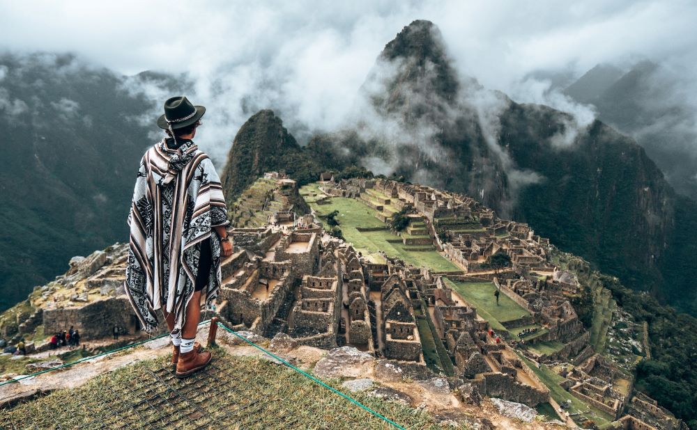 homme au sommet du machu picchu habillé poncho local chapeau regardant le village en terrasse paysage de rêve
