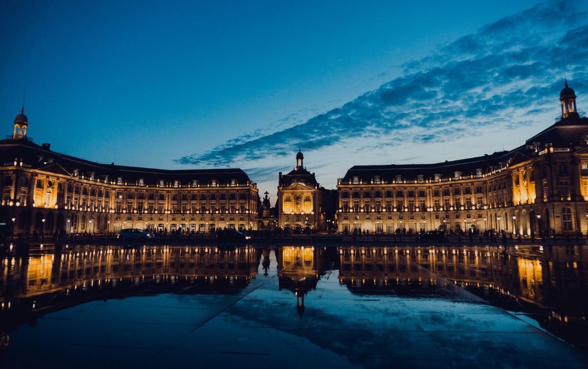 Place de la Bourse et miroir d'eau de Bordeaux illuminés la nuit, cadre d'un team building en ville