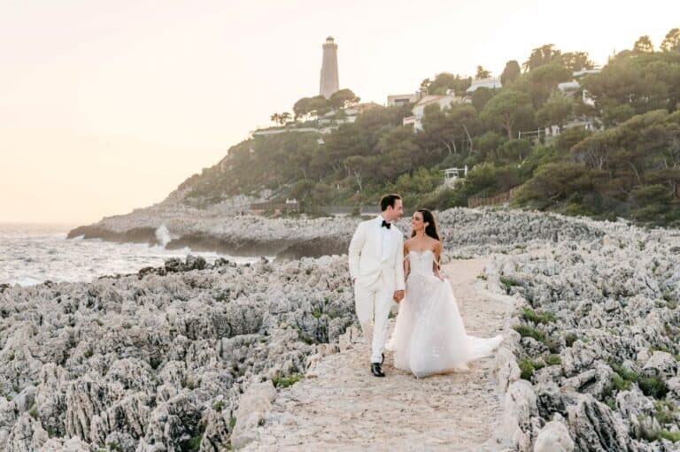 mariage de rêve à la plage sentier côtier devant phare photographie des mariés en blanc costume crème robe blanche