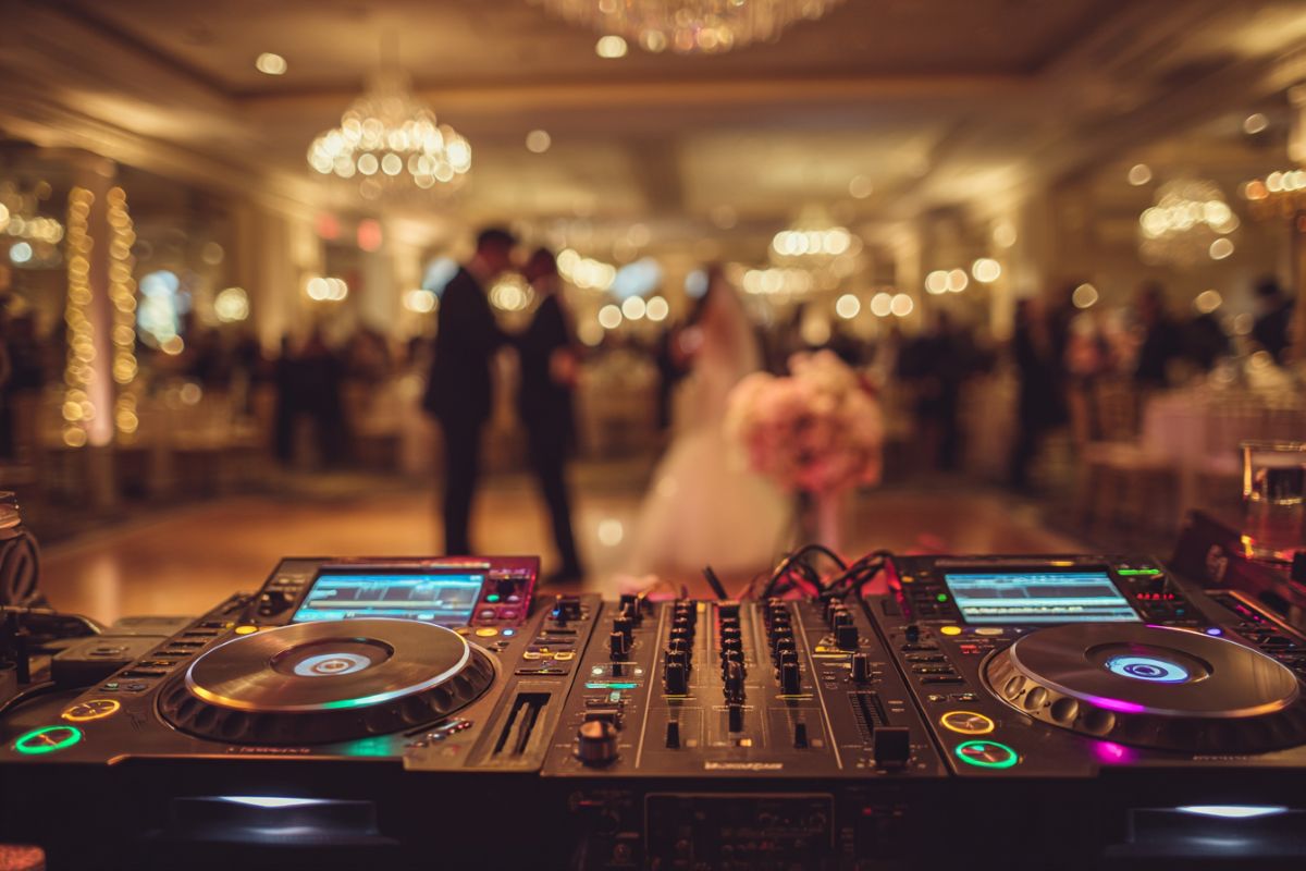 DJ professionnel mixant lors d'une soirée de mariage avec platines et éclairages LED colorés