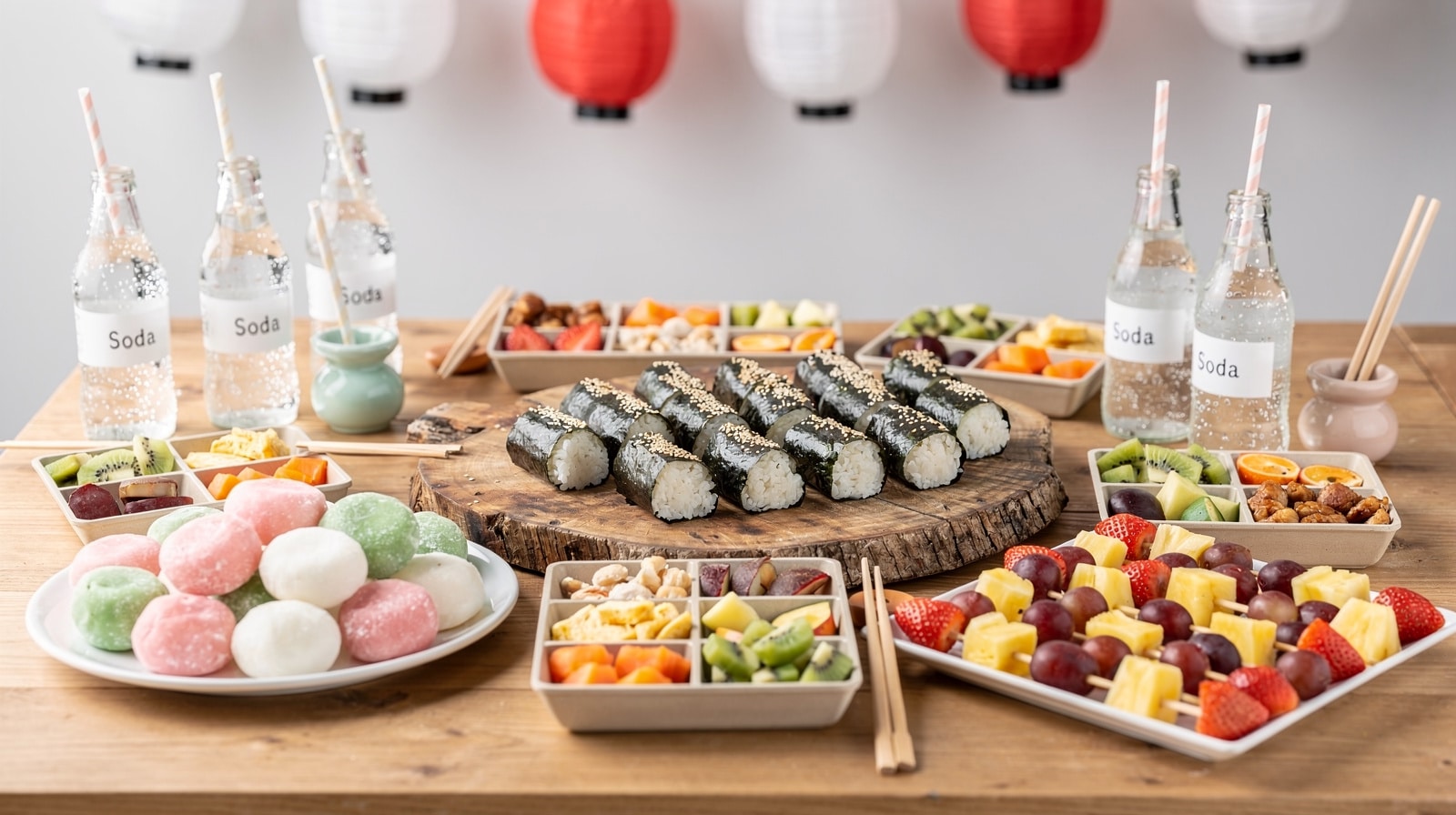 Goûter d'anniversaire japonais : onigiri, mochis, brochettes de fruits et bento colorés sous des lanternes