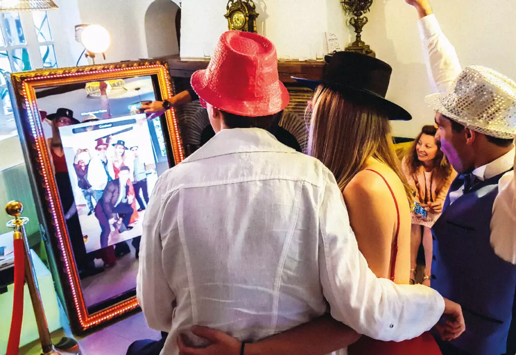 trois personnes avec chapeau se prennent en photo devant le miroir photobooth shootnbox lors d'un mariage animé