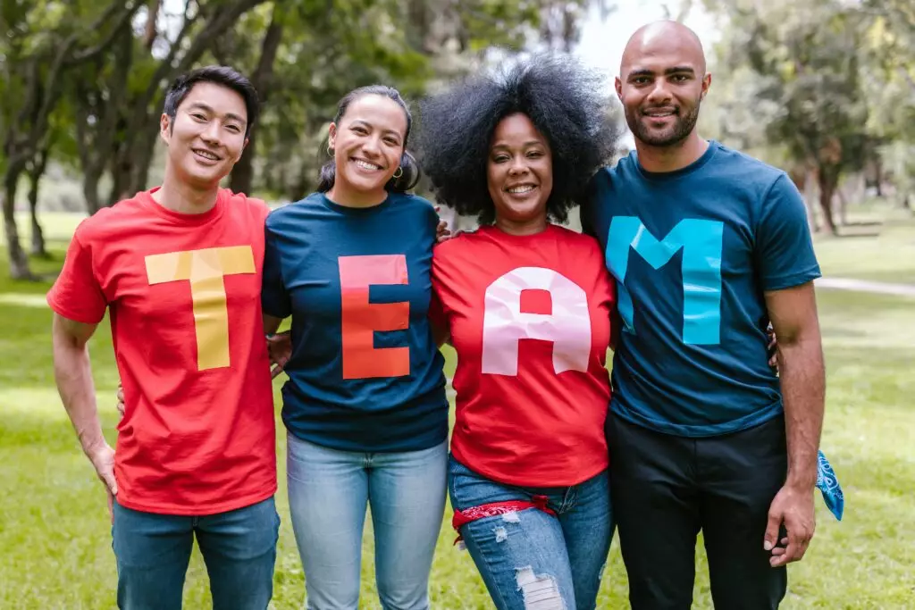 4 personnes portant chacun un t-shirt avec des lettres formant le mot team