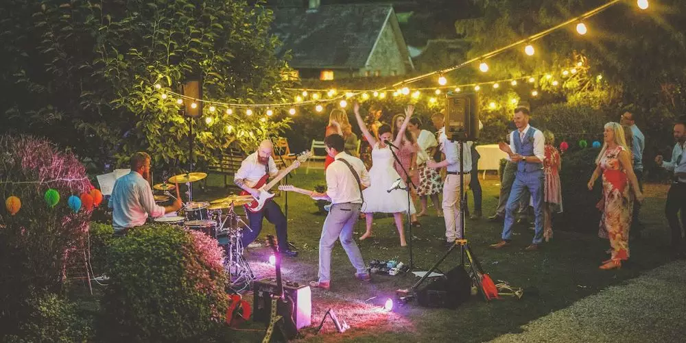 petit mariage entre amis dans un jardin en été guirlande lumineuse groupe de musique avec guitare électrique