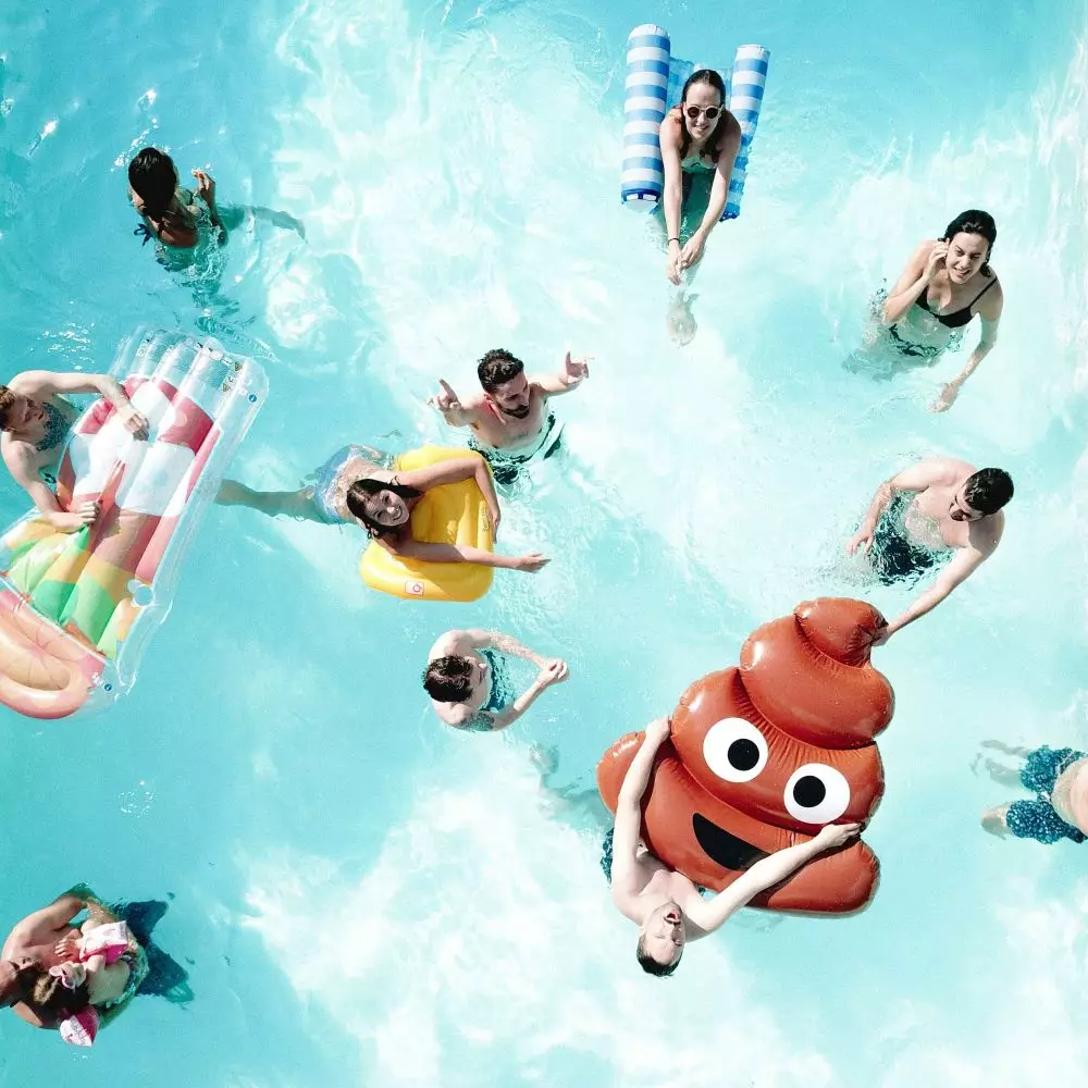 plusieurs jeunes adultes dans une piscine avec bouée gonflable emoji caca poop pool party